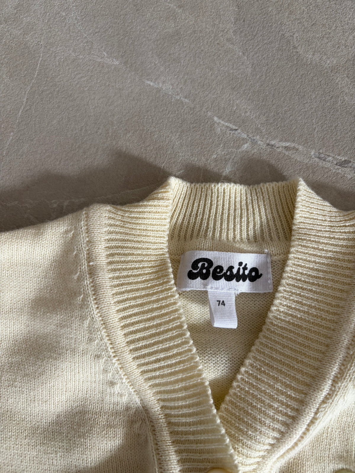 een detail foto van de voorkant van het merino wollen vestje van besito baby in een botergele kleur