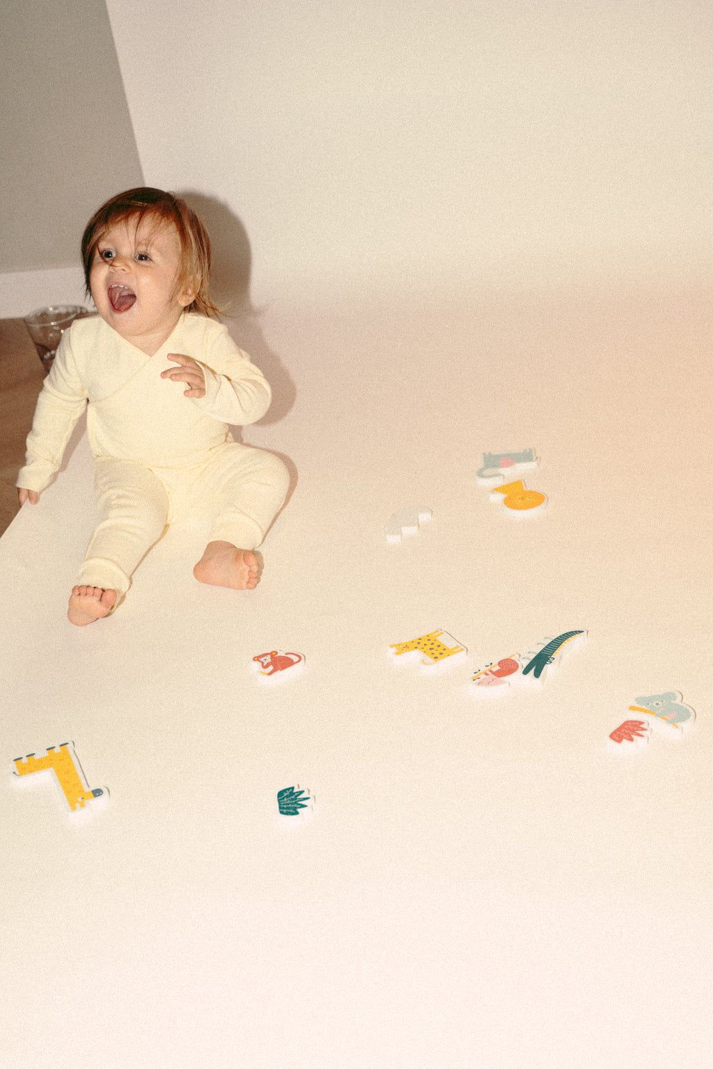 een baby die blij lacht in het botergele pakje van besito baby