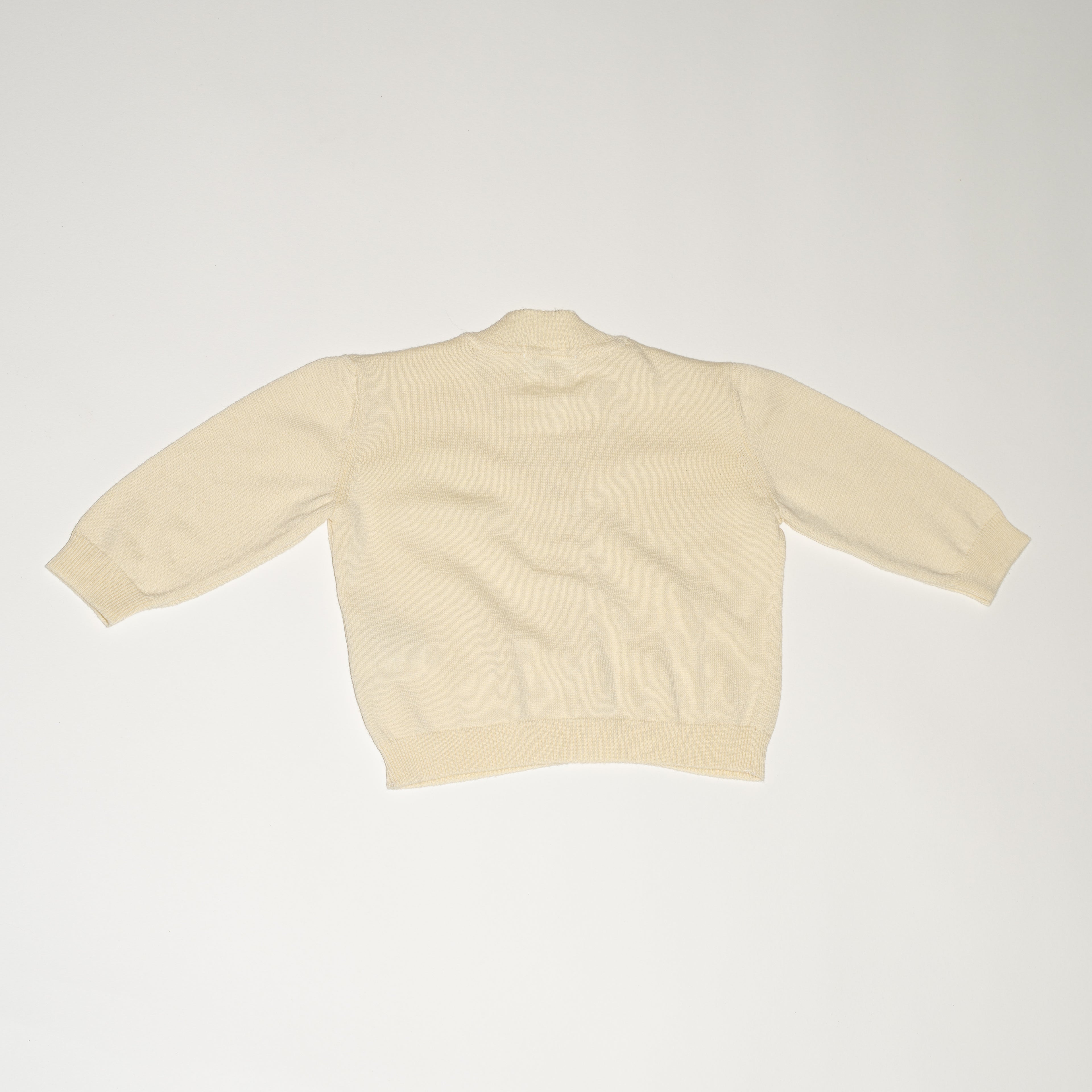 de achterkant van de merino wollen cardigan van besito baby in butter yellow