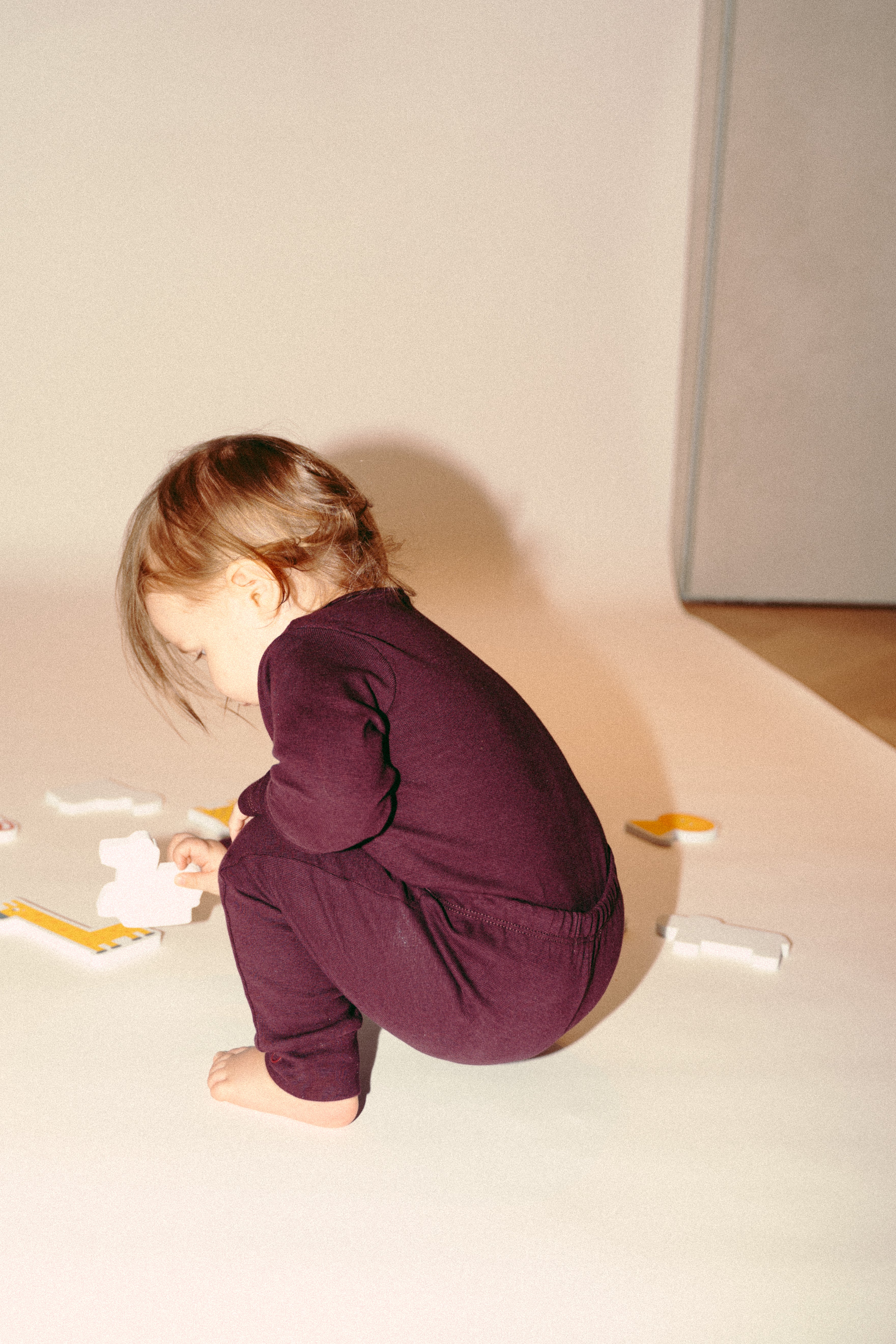 een baby die gehurkt zit in de chocolate bordeaux outfit van besito baby