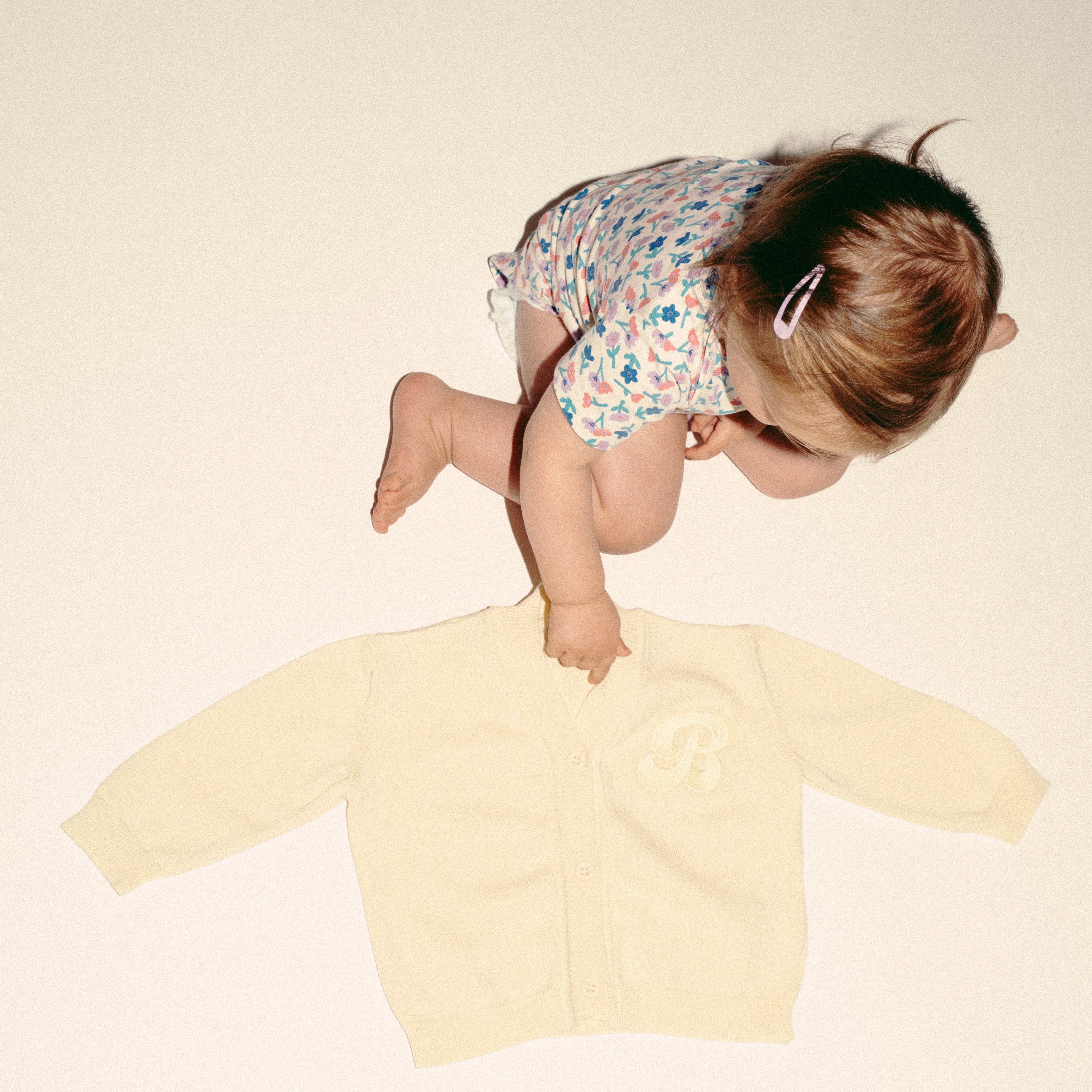 een foto van de cardigan van merino wol met een baby in beeld in de kleur butter yellow van besito baby