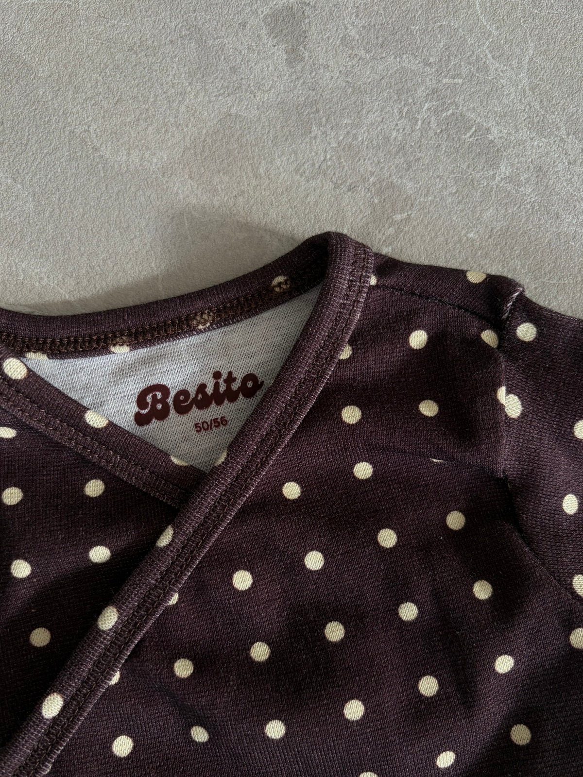 een detail foto van het overslag rompertje van Besito Baby in een polka dot print