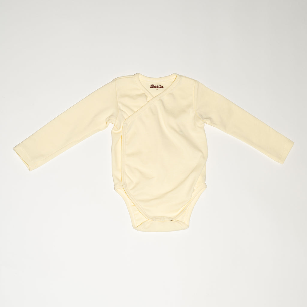 de voorkant van de wrap bodysuit van besito baby in de kleur butter yellow