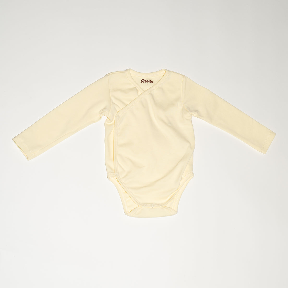 de voorkant van de wrap bodysuit van besito baby in de kleur butter yellow